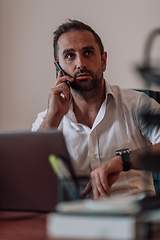 Image showing A businessman talking on his smartphone while seated in an office, showcasing his professional demeanor and active communication.