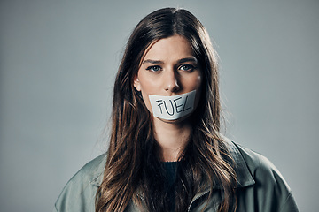 Image showing Woman, face and tape mouth for fuel prices or economy struggle against gray studio background. Portrait of female activist with covered lips in silence of speech for voice message or financial crisis