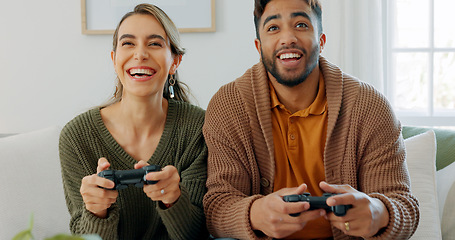 Image showing Fun, playing and love with a gamer couple laughing, joking or bonding while gaming on a sofa in the living room of their home together. Game, funny and laugh with a man and woman enjoying video games