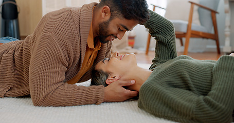 Image showing Couple, kiss or bonding on floor in house or relax home in love, trust or security. Smile, happy or talking interracial man or woman lying on living room carpet in intimate, romance or support moment