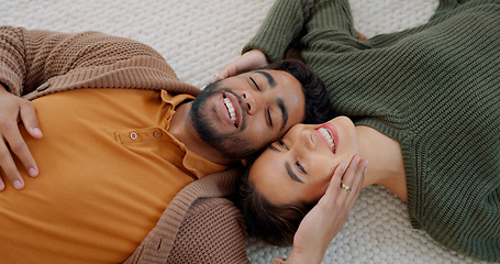 Image showing Kiss, love and couple on the floor of their living room to relax with happiness together in their house. Comic, happy and man and woman with smile for affection and funny conversation from above