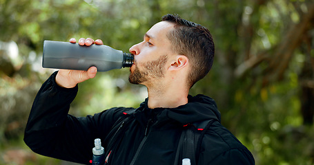 Image showing Hiking, nature and man drinking water in bottle while on outdoor adventure trail hike in forest. Travel, freedom and healthy young guy enjoying refreshing drink for hydration while trekking in woods.