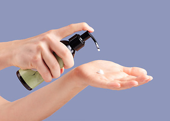 Image showing Moisturizer, skincare and hands with a bottle for cream isolated on a blue background in studio. Beauty, cosmetic and woman with lotion or sunscreen in palm for moisture, treatment and grooming