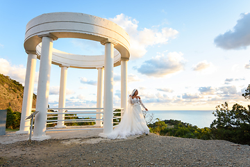 Image showing Portrait of a bride in a wedding dress in a beautiful gazebo with columns on the seashore