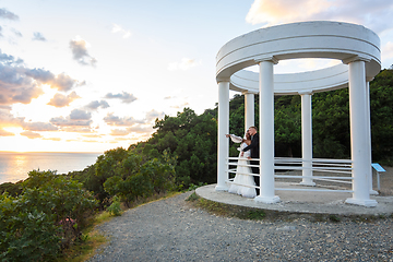 Image showing Newlyweds in a gazebo with columns on the seashore in the rays of the setting sun