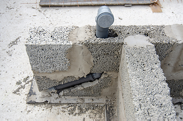 Image showing Laying a sewer pipe in the bathroom wall during the construction of a house