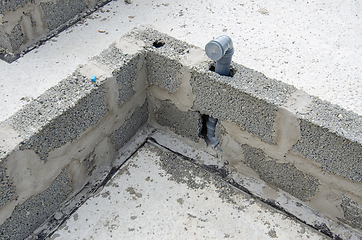 Image showing Sewerage pipe immured into the wall during the construction of walls from expanded clay concrete blocks