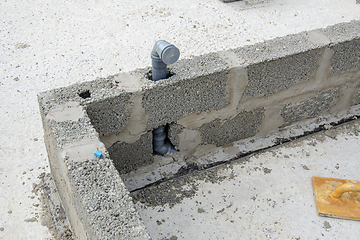 Image showing The sewer pipe is immured into the wall during the construction of walls from expanded clay concrete blocks