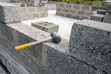 Image showing A mallet lies on a part of a wall made of expanded clay concrete blocks during the construction of walls