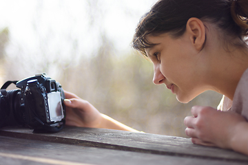 Image showing A girl looks at the screen of a SLR camera