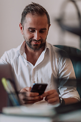 Image showing A businessman using on his smartphone while seated in an office, showcasing his professional demeanor and active communication.