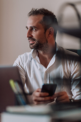 Image showing A businessman using on his smartphone while seated in an office, showcasing his professional demeanor and active communication.