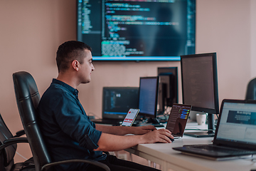 Image showing A programmer diligently testing smartphone applications while sitting in their office.