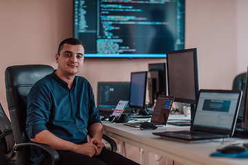 Image showing A programmer diligently testing smartphone applications while sitting in their office.