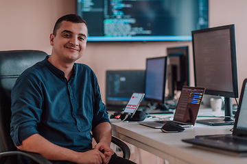 Image showing A programmer diligently testing smartphone applications while sitting in their office.