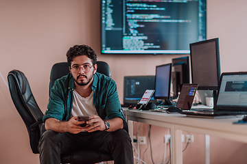 Image showing A programmer diligently testing smartphone applications while sitting in their office.