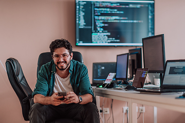 Image showing A programmer diligently testing smartphone applications while sitting in their office.