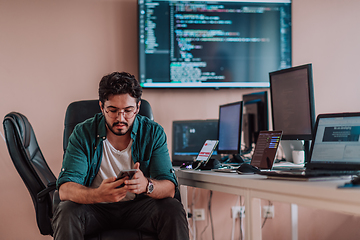 Image showing A programmer diligently testing smartphone applications while sitting in their office.