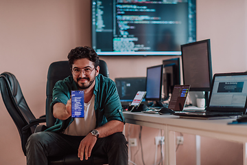 Image showing A programmer diligently testing smartphone applications while sitting in their office.