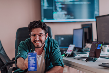 Image showing A programmer diligently testing smartphone applications while sitting in their office.