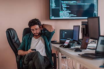 Image showing A programmer diligently testing smartphone applications while sitting in their office.