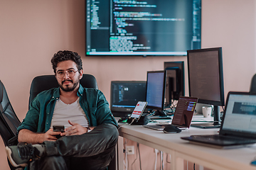 Image showing A programmer diligently testing smartphone applications while sitting in their office.