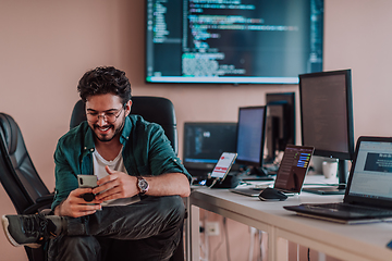 Image showing A programmer diligently testing smartphone applications while sitting in their office.