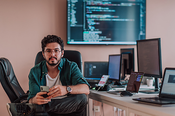 Image showing A programmer diligently testing smartphone applications while sitting in their office.