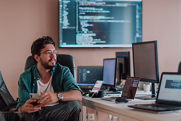 Image showing A programmer diligently testing smartphone applications while sitting in their office.