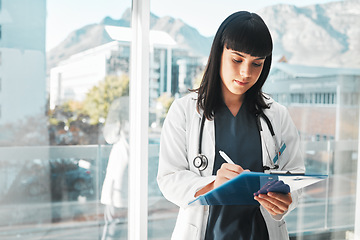 Image showing Woman, doctor and writing on clipboard by window for healthcare planning, strategy or notes at hospital. Female medical expert with paperwork, prescription or write for medicare details at clinic