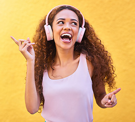 Image showing Music, thinking and dance with a black woman listening to the radio outdoor on a yellow wall background. Headphones, energy and face with an attractive young female streaming audio sound for fun