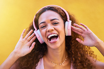 Image showing Music, portrait and laughter with a black woman listening to the radio outdoor on a yellow wall background. Headphones, energy and face with an attractive young female streaming audio sound for fun