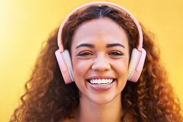 Image showing Music, portrait and smile with a black woman listening to the radio outdoor on a yellow wall background. Headphones, energy and face with an attractive young female streaming audio sound for fun