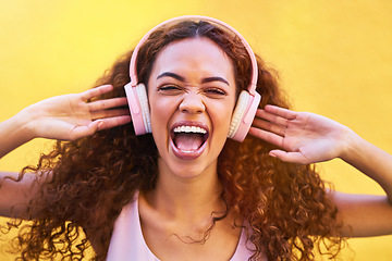 Image showing Music, face and shouting with a black woman listening to the radio outdoor on a yellow wall background. Headphones, energy and face with an attractive young female streaming audio sound for fun