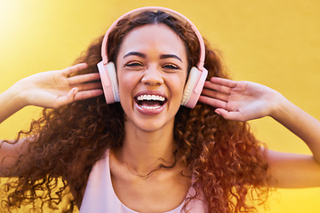 Image showing Music, portrait and freedom with a black woman listening to the radio outdoor on a yellow wall background. Headphones, energy and face with an attractive young female streaming audio sound for fun