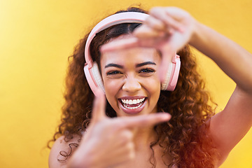 Image showing Music, frame and face with a black woman listening to the radio outdoor on a yellow wall background. Headphones, energy and face with an attractive young female streaming audio sound for fun