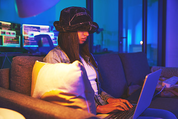 Image showing Woman, hacker and programmer typing on laptop in home at night in neon to hack software. Cybersecurity sofa, ransomware phishing and female coder coding on computer for hacking database with malware.