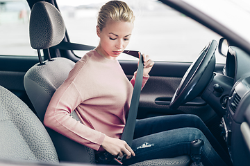 Image showing Beautiful woman fastening seat belt in small personal car.