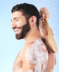 Image showing Shower, cleaning and man with brush, water splash and soap in studio for wellness, hygiene and grooming. Skincare, self care and male with foam, bath cosmetics and washing body on blue background