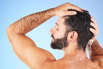 Image showing Man, shower and hair wash of a model in water for cleaning, skincare and hygiene wellness. Isolated, blue background and studio with a young person in bathroom for dermatology and self care routine