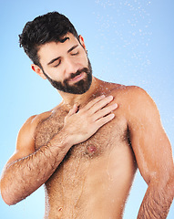 Image showing Water drops, shower and man for hygiene self care and cleaning on a blue background in studio. Body of a aesthetic model person for skincare, health and wellness with splash for dermatology cosmetics