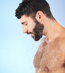 Image showing Man, water and profile of a model in shower for cleaning, skincare and hygiene wellness. Isolated, blue background and studio with a young person in bathroom for facial dermatology and mockup