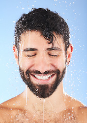 Image showing Man, shower water and smile of a model for beauty cleaning, skincare and hygiene wellness. Isolated, blue background and studio with a young person in bathroom for dermatology and self care routine