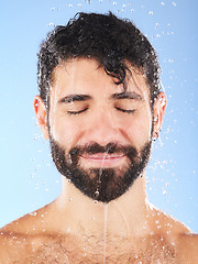 Image showing Man, water drop and face for hygiene, self care and cleaning on blue background in studio. Aesthetic model person for skincare, health and wellness with shower splash for facial dermatology cosmetics