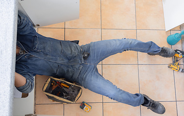 Image showing Top, plumber and man on floor of maintenance service, engineering or renovation in house. Above of handyman, plumbing and contractor working with mechanic tools for home pipe, upgrade or installation