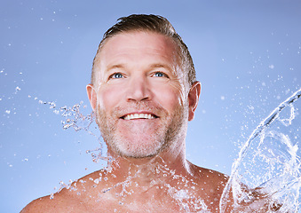 Image showing Wellness, water splash and senior man cleaning, morning routine and washing on blue studio background. Male, mature gentleman and daily hygiene with clear liquid for dermatology, skincare or grooming