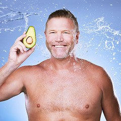 Image showing Beauty, water splash with man and avocado for skincare, eco friendly and vegan cosmetics on blue background. Hygiene, hydration and mature male smile in portrait, detox facial and fruit with face