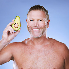 Image showing Beauty, portrait with man and avocado for skincare, eco friendly and vegan cosmetics on blue background. Hygiene, organic product and mature male with smile, detox facial and fruit with face care