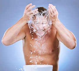 Image showing Man, water splash and face wash by basin for hygiene or natural sustainability against a blue studio background. Male washing by sink for clean wellness, skincare or self care for facial treatment