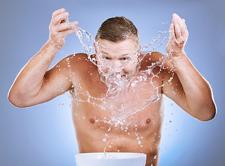 Image showing Man cleaning face, skincare and water splash, hygiene and grooming with clean facial on blue background. Washing skin, basin and morning routine with natural cosmetic care, wellness and dermatology